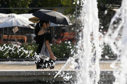 A woman shelters from the sun with an umbrella as she walks next a public fountain in Milan, Italy, Friday, July 21, 2023. The new heat wave in several parts of southern Europe is expected to persist for days. The U.N. weather agency said that temperatures in Europe, amplified by climate change, could break the 48.8-degree Celsius (119.8-degree Fahrenheit) record set in Sicily two years ago. (AP Photo/Antonio Calanni)